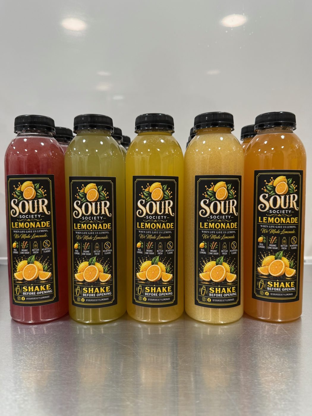 A lineup of Sour Society lemonade bottles in five flavors