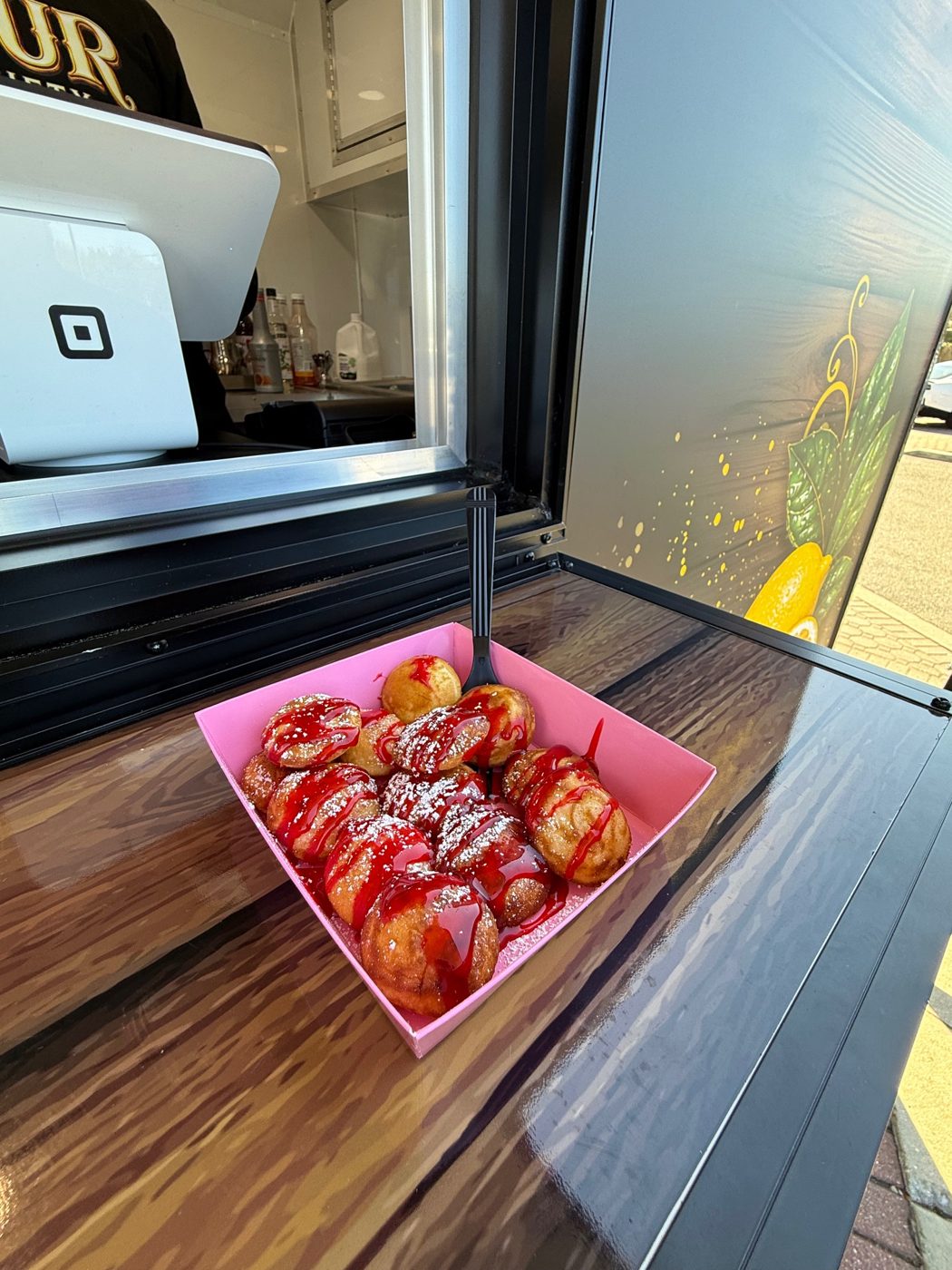Mini pancakes with strawberry drizzle in a pink tray at the trailer window